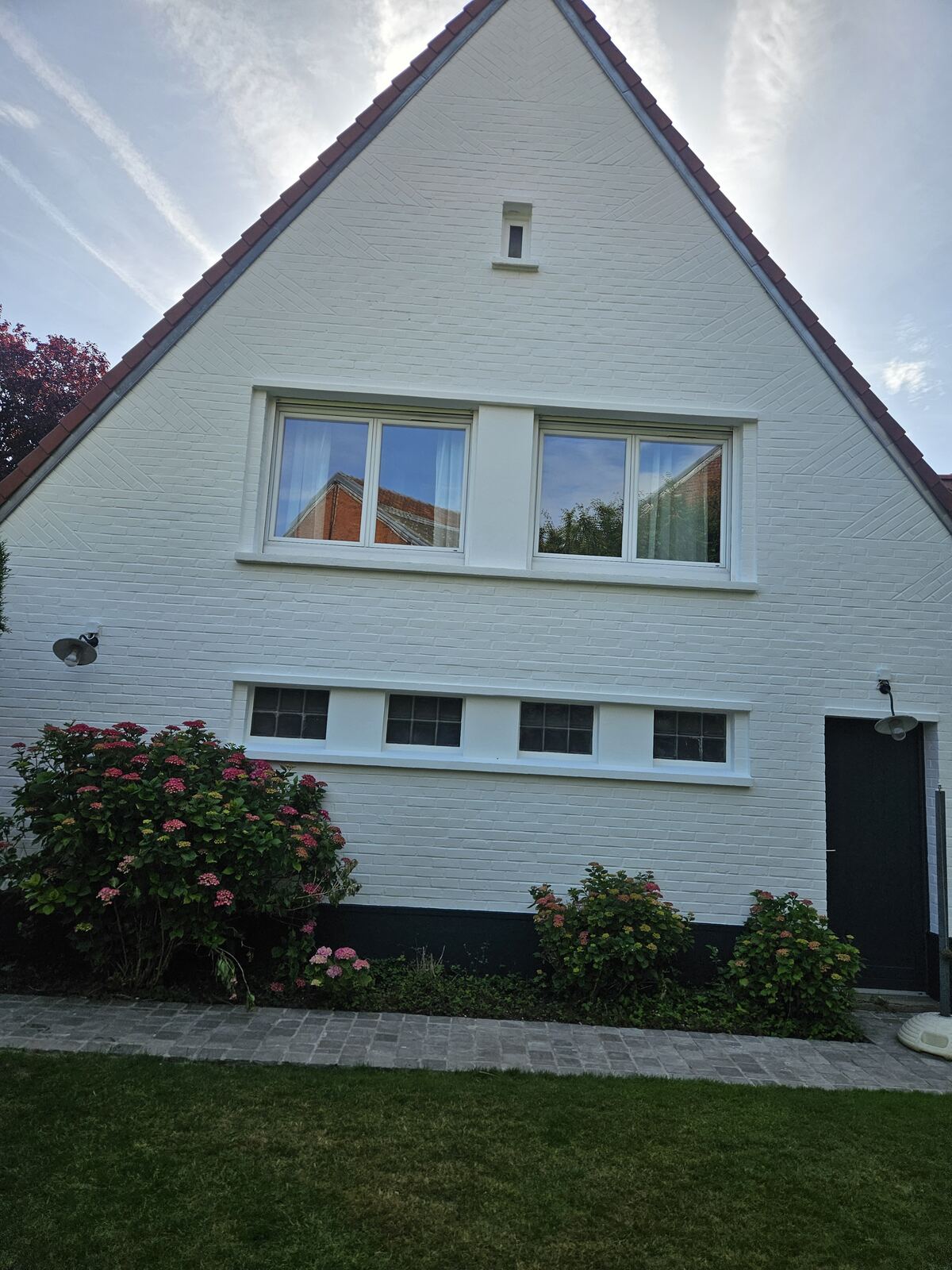 Façade de maison peinte en blanc, jardin fleuri