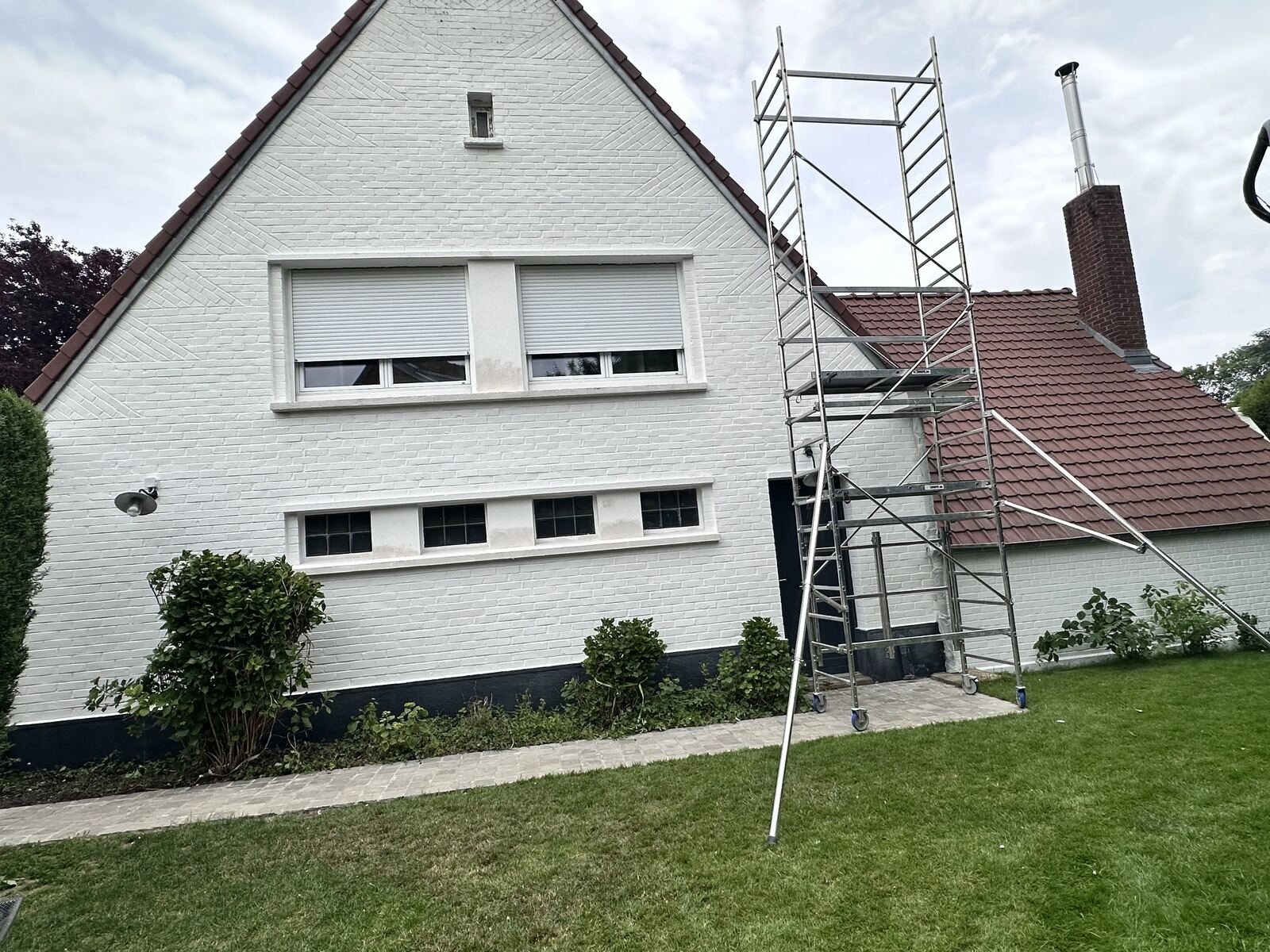 Maison en briques peintes en blanc avec échafaudage