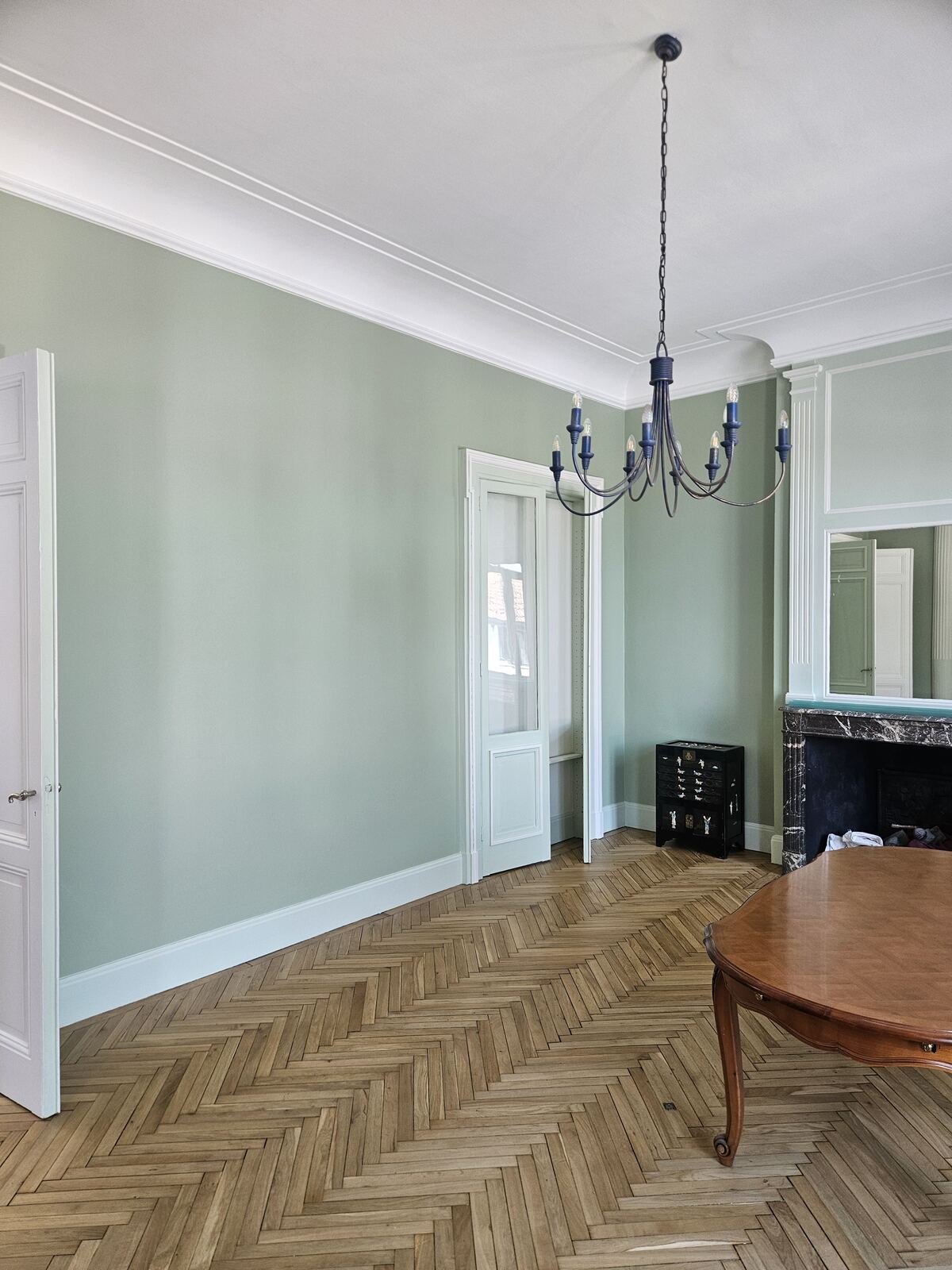 Pièce peinte en vert sauge avec moulures et parquet